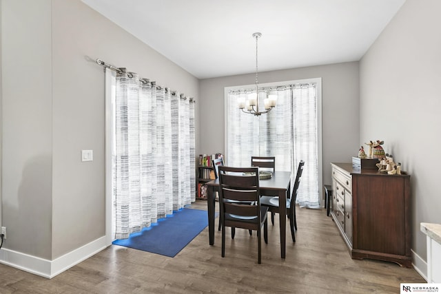 dining area featuring a chandelier, wood finished floors, and baseboards