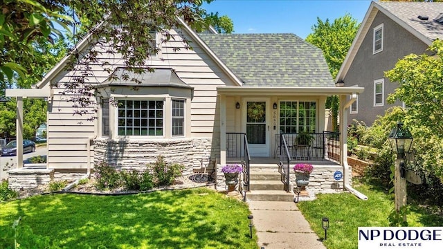 5650 Poppleton Ave, Omaha, NE 68106 - tudor house featuring a front yard, roof with shingles, and stone siding