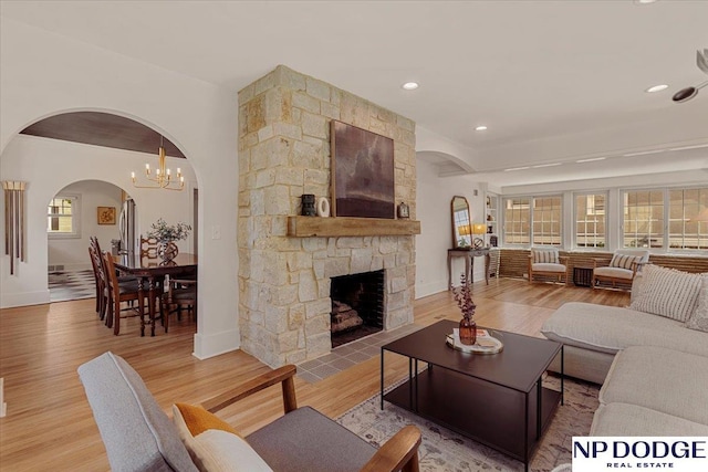 5650 Poppleton Ave, Omaha, NE 68106 - living room featuring arched walkways, light wood-style flooring, a stone fireplace, baseboards, and recessed lighting