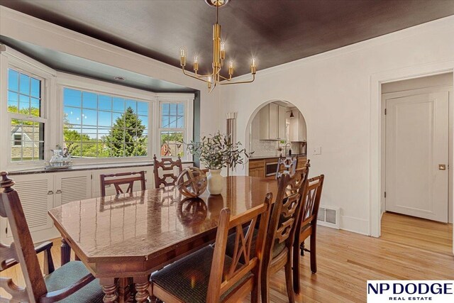 5650 Poppleton Ave, Omaha, NE 68106 - dining room with arched walkways, a chandelier, light wood-style floors, ornamental molding, and baseboards