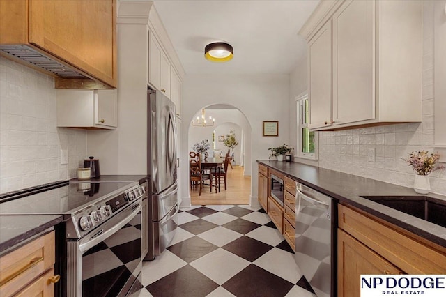 5650 Poppleton Ave, Omaha, NE 68106 - kitchen featuring stainless steel appliances, arched walkways, dark floors, and backsplash