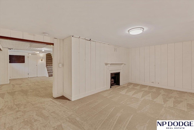 5650 Poppleton Ave, Omaha, NE 68106 - unfurnished living room featuring carpet flooring, stairway, a fireplace, and wood walls
