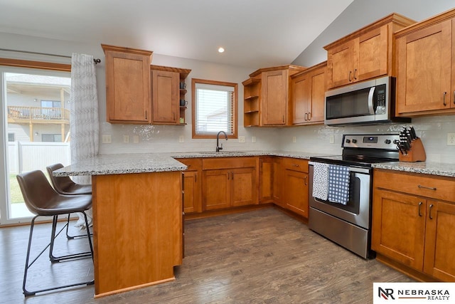 kitchen featuring stainless steel appliances, open shelves, a sink, brown cabinetry, and lofted ceiling