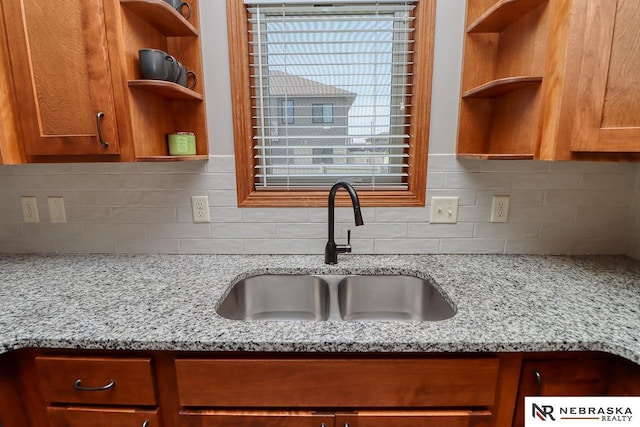 kitchen featuring open shelves, a sink, and light stone countertops