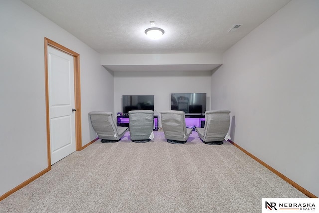 sitting room featuring carpet floors, baseboards, and a textured ceiling