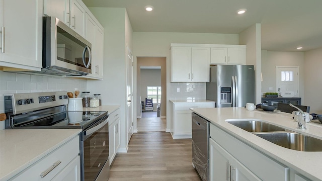 kitchen featuring appliances with stainless steel finishes, a sink, white cabinetry, and recessed lighting