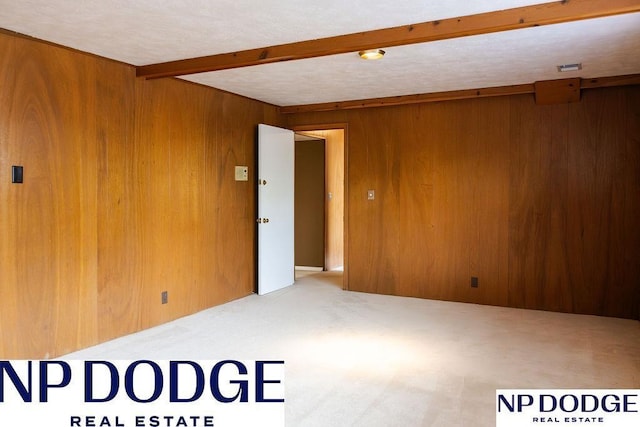 unfurnished room featuring wooden walls, carpet, and beam ceiling
