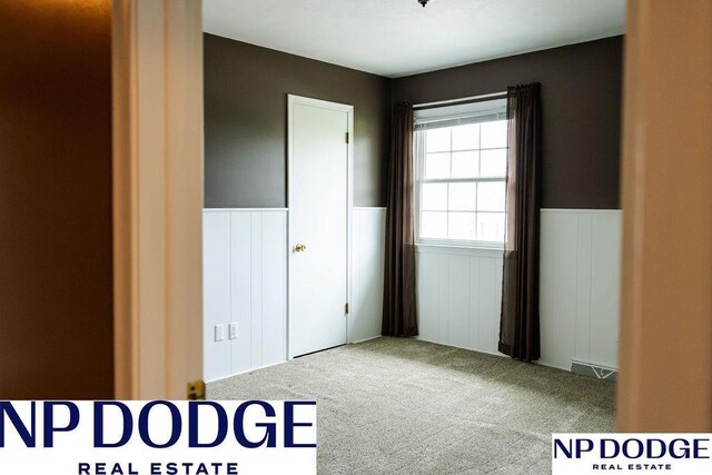 unfurnished bedroom with a wainscoted wall and carpet floors
