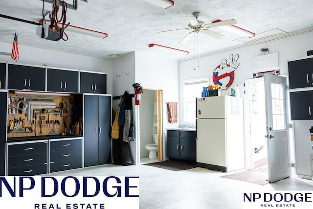 kitchen featuring freestanding refrigerator, dark cabinetry, healthy amount of natural light, and a textured ceiling