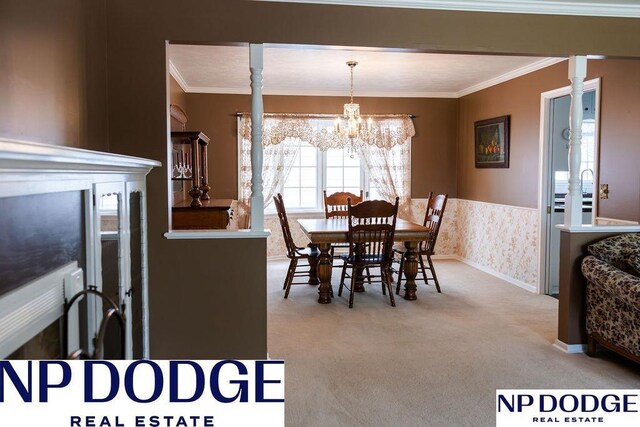 carpeted dining area featuring a chandelier, crown molding, and wainscoting