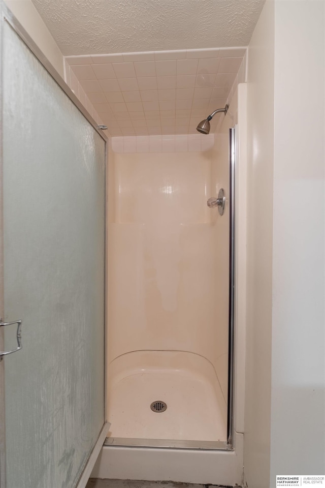 full bath featuring a stall shower and a textured ceiling
