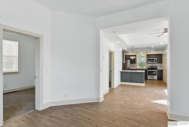 unfurnished living room featuring light wood-style floors, baseboards, and a ceiling fan