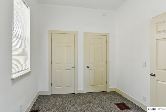 unfurnished bedroom with dark carpet and baseboards