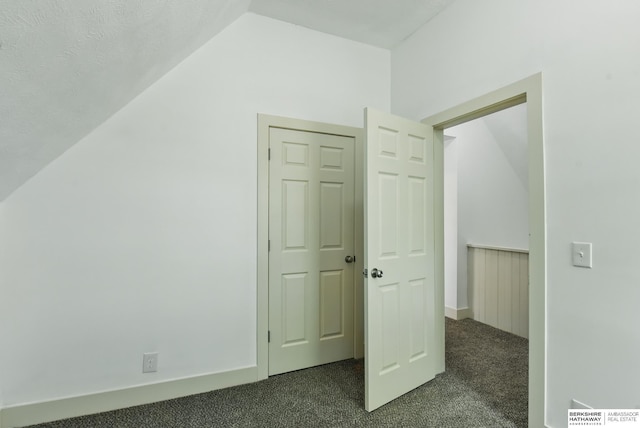 additional living space with dark colored carpet and lofted ceiling