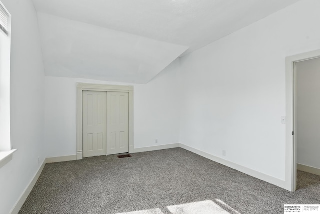 unfurnished bedroom with carpet, lofted ceiling, a closet, and baseboards
