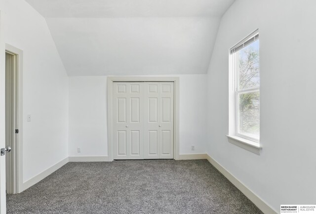 unfurnished bedroom with lofted ceiling, carpet, baseboards, and a closet