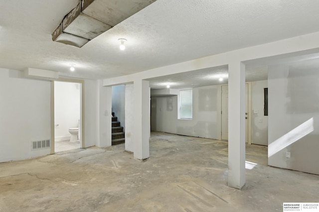 basement with stairs and a textured ceiling