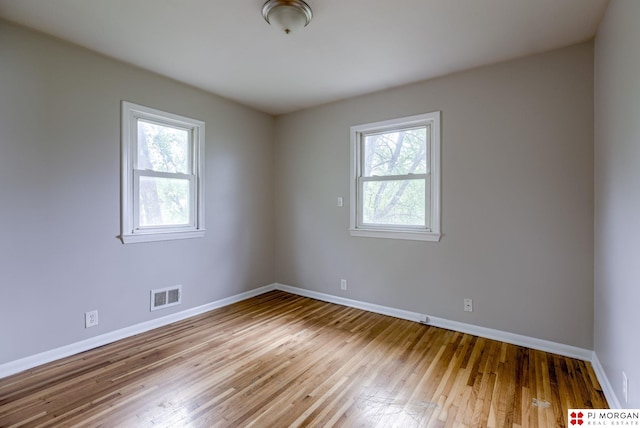 unfurnished room featuring plenty of natural light, baseboards, and wood-type flooring