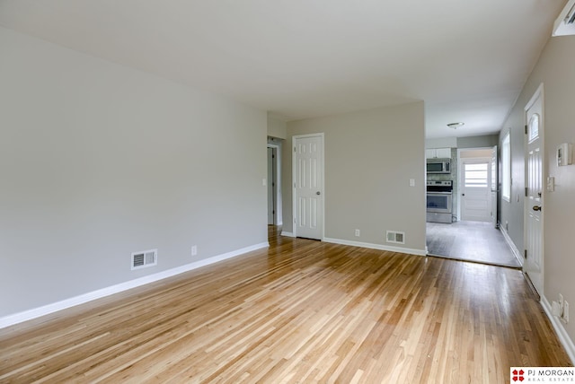 empty room featuring light wood-type flooring and baseboards