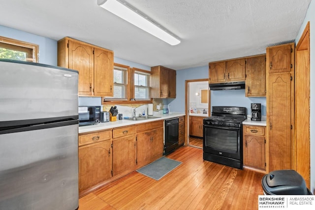 929 Main St, Seward, NE 68434 - kitchen with black appliances, under cabinet range hood, light wood-style flooring, a sink, and plenty of natural light