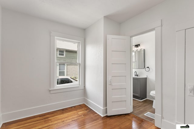 2139 S 8th St, Lincoln, NE 68502 - unfurnished bedroom with hardwood / wood-style flooring, baseboards, a sink, and connected bathroom