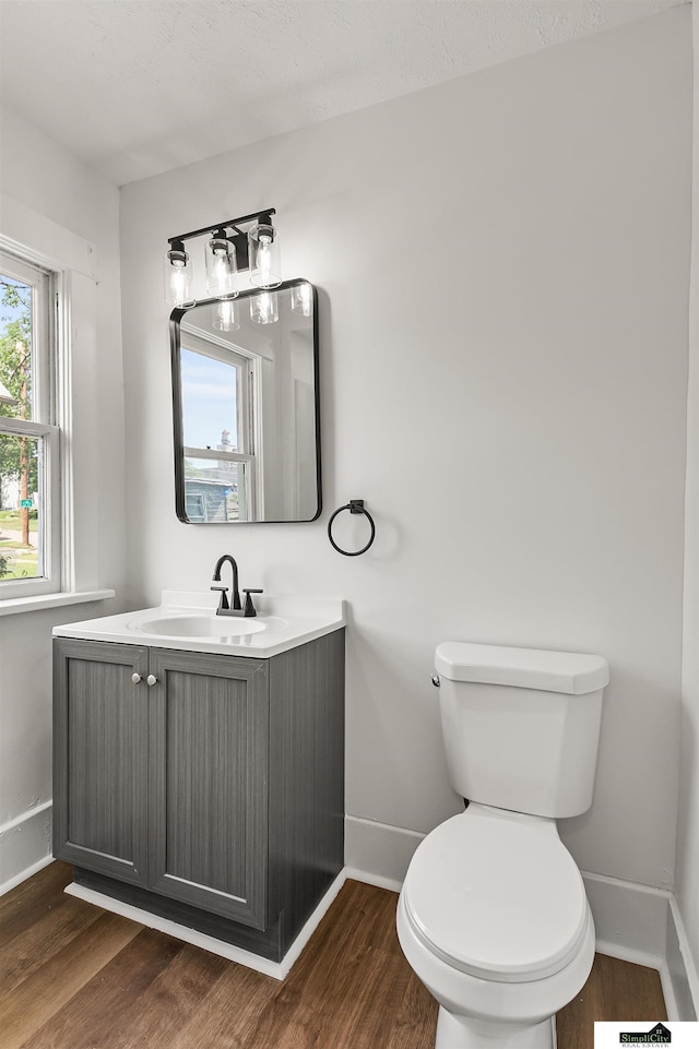 2139 S 8th St, Lincoln, NE 68502 - half bath with baseboards, wood finished floors, toilet, and vanity
