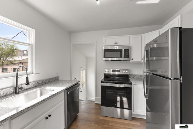 2139 S 8th St, Lincoln, NE 68502 - kitchen with appliances with stainless steel finishes, a sink, white cabinetry, light wood finished floors, and light stone countertops