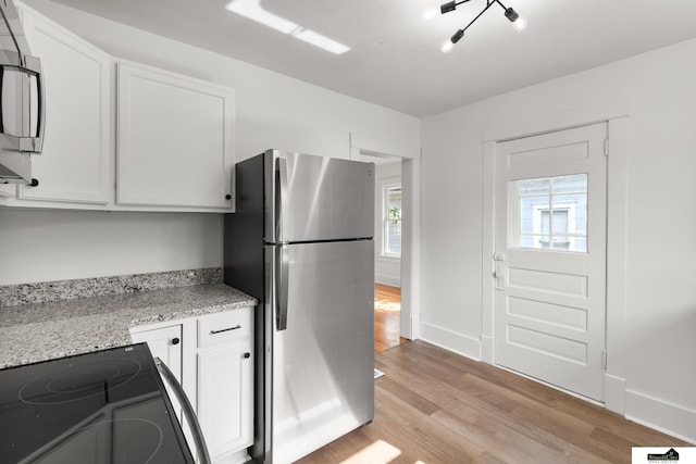 2139 S 8th St, Lincoln, NE 68502 - kitchen featuring stainless steel appliances, light wood-type flooring, white cabinetry, and light stone counters