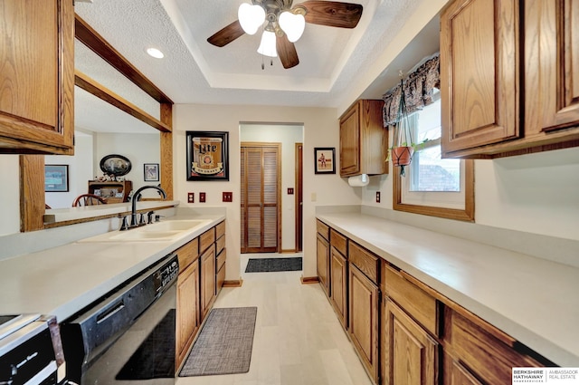 kitchen with black dishwasher, a sink, a tray ceiling, brown cabinets, and recessed lighting