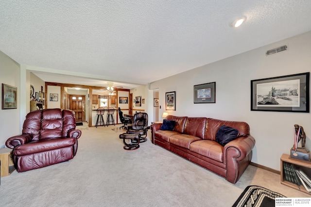 living area featuring carpet flooring, a textured ceiling, and a ceiling fan