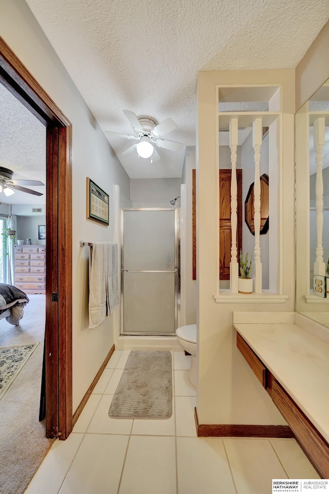 bathroom featuring ceiling fan, a stall shower, baseboards, a textured ceiling, and toilet