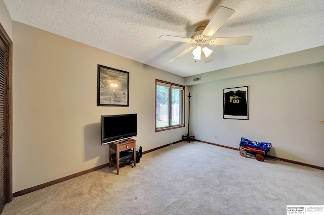 unfurnished room featuring light colored carpet, a textured ceiling, baseboards, and a ceiling fan