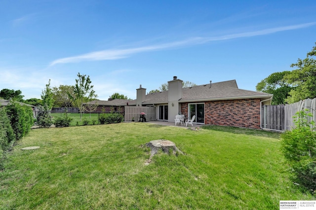 rear view of property with a patio area, a chimney, brick siding, and roof with shingles