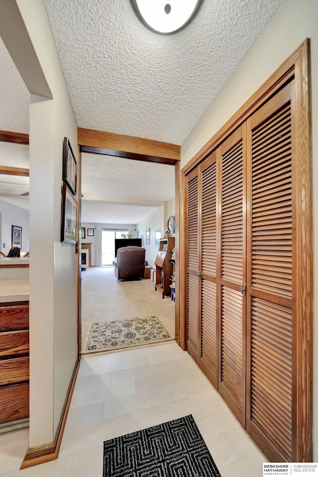 hall featuring a textured ceiling and beam ceiling