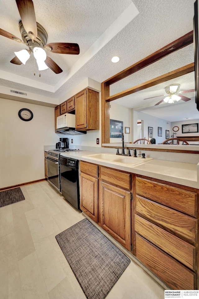 kitchen featuring a sink, black dishwasher, a textured ceiling, ceiling fan, and brown cabinets