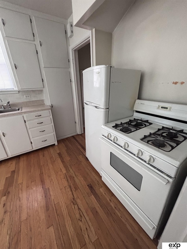 kitchen with white appliances, wood-type flooring, a sink, white cabinets, and light countertops