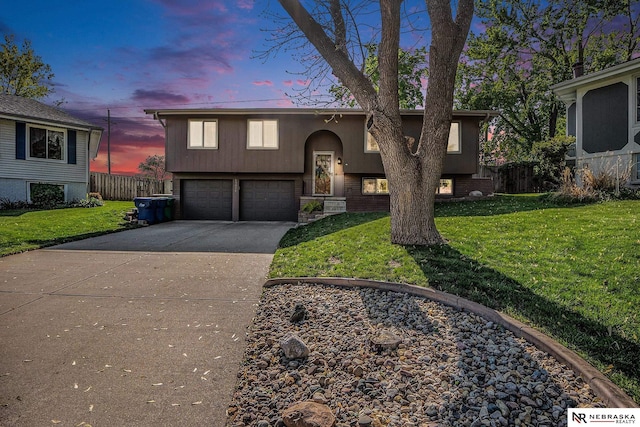 raised ranch featuring concrete driveway, an attached garage, and stucco siding