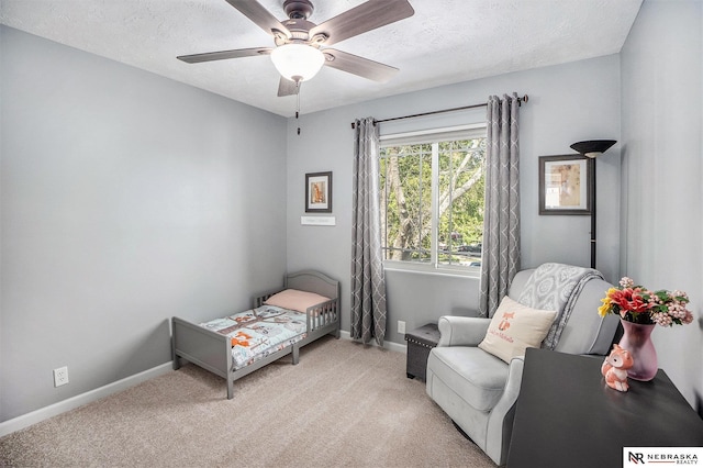 bedroom with light carpet, baseboards, a textured ceiling, and a ceiling fan