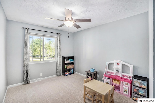 playroom featuring baseboards, carpet flooring, ceiling fan, and a textured ceiling