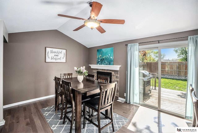 dining area featuring a ceiling fan, wood finished floors, baseboards, lofted ceiling, and a fireplace
