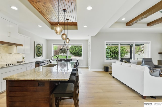 kitchen with a tray ceiling, plenty of natural light, a sink, black electric cooktop, and recessed lighting