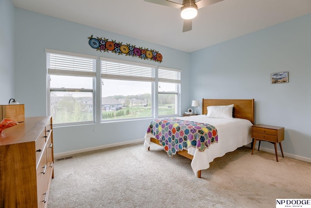 bedroom with multiple windows, light carpet, and baseboards