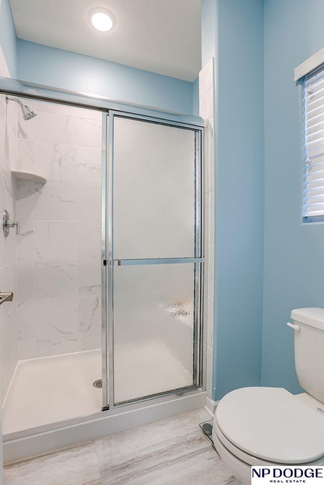 bathroom with toilet, a stall shower, and wood finished floors