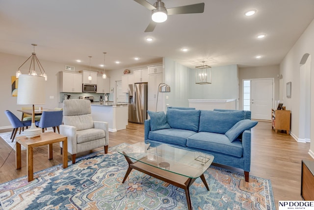 living area featuring ceiling fan, light wood finished floors, baseboards, and recessed lighting