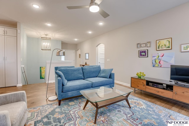 living room featuring arched walkways, wood finished floors, a ceiling fan, recessed lighting, and a chandelier