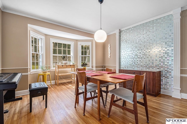 dining space featuring ornate columns, wood finished floors, baseboards, and ornamental molding
