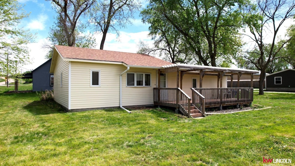 back of property featuring a lawn and a shingled roof