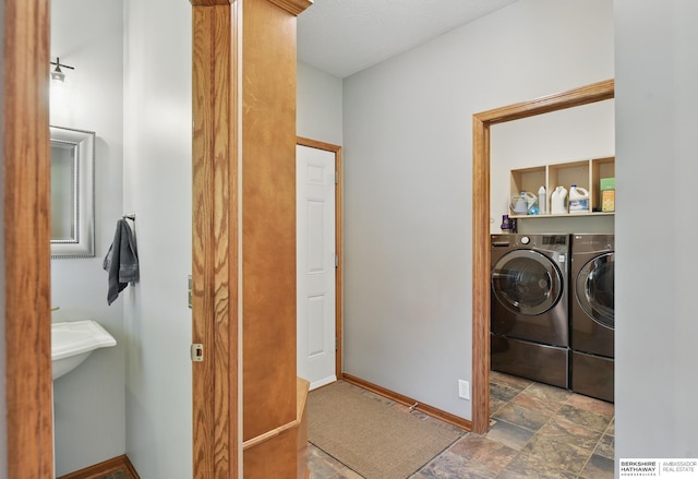 laundry area featuring washer and clothes dryer, baseboards, and stone finish floors