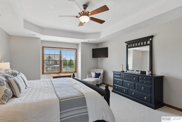 carpeted bedroom with a tray ceiling, baseboards, and a ceiling fan