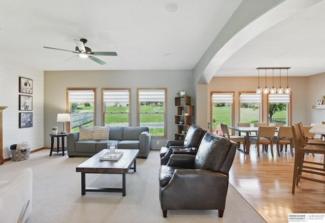living room with plenty of natural light, a ceiling fan, arched walkways, and baseboards